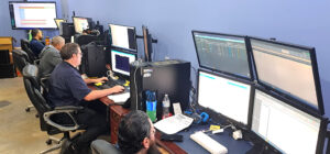 IT support staff working at desks with multiple large monitors